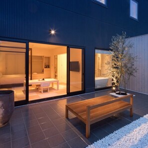 A modern house with a patio area featuring a wooden bench and a small tree. - Solest Takachiho Hotel (Takachiho)