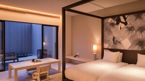 Une chambre d’hôtel moderne avec un grand lit, un bureau et une chaise. Une grande fenêtre offre une vue sur l’extérieur.