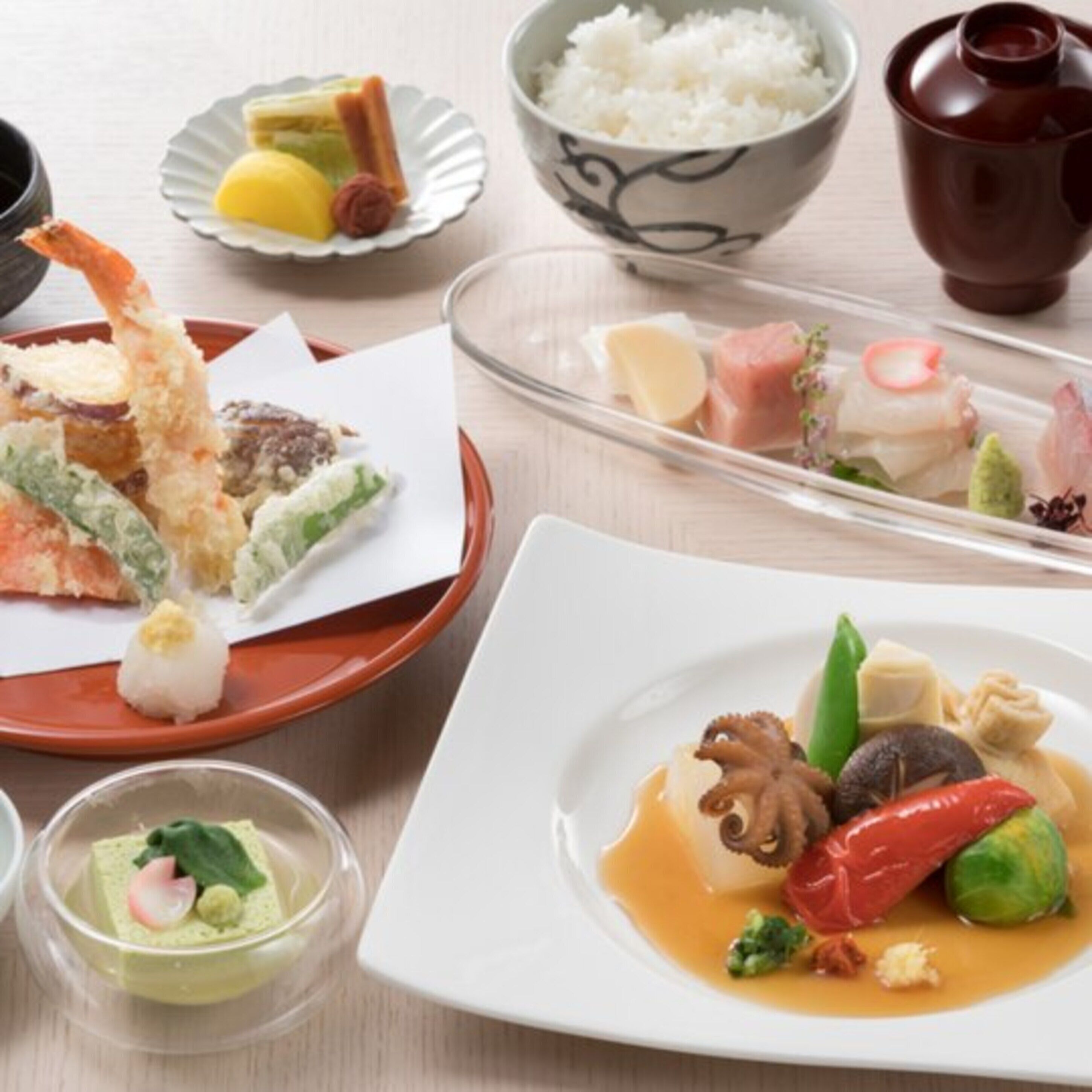 A variety of Japanese dishes including sushi, tempura, and sashimi, served on traditional ceramic plates and bowls.