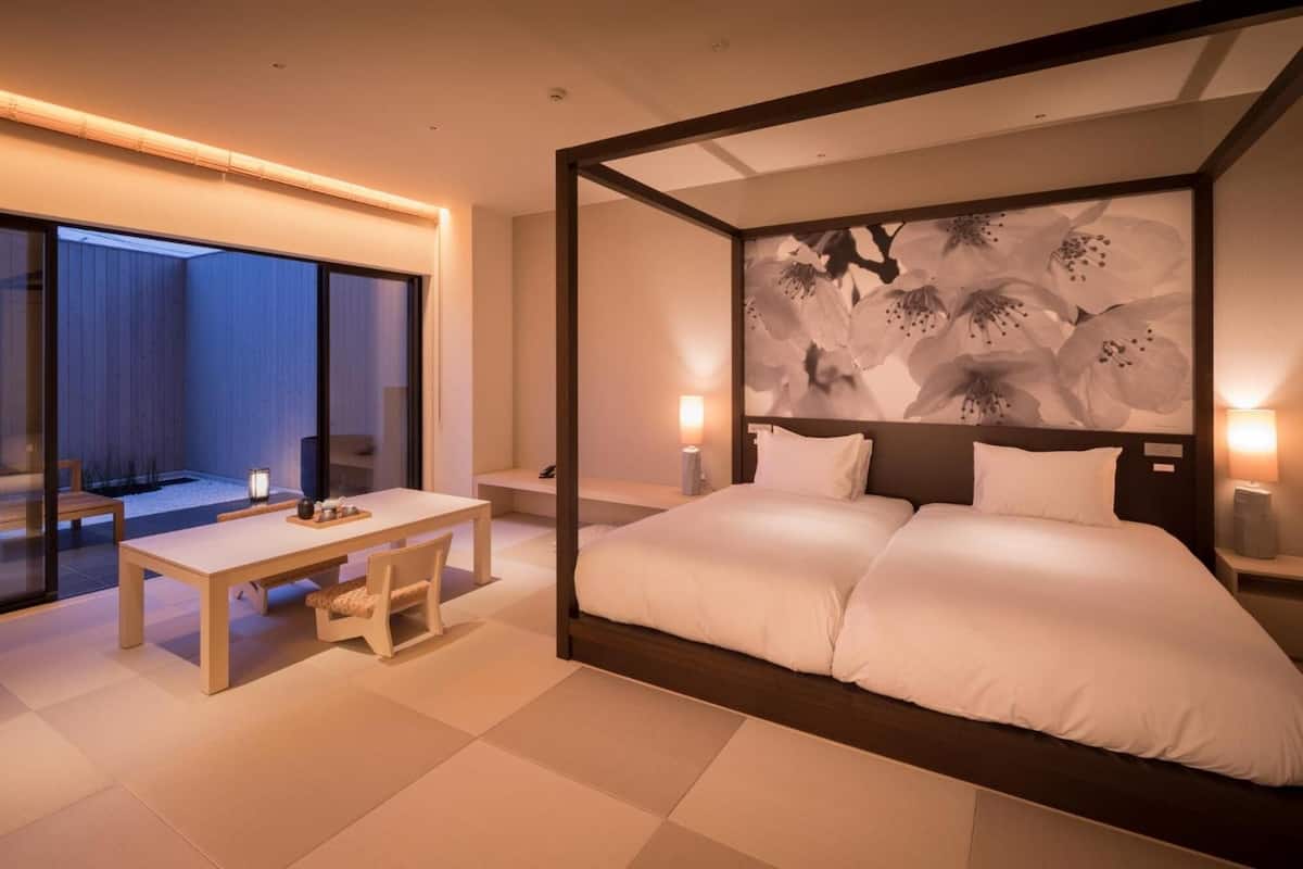 Un dormitorio moderno con una cama grande, una mesita de noche y vistas a un jardín a través de un ventanal.
