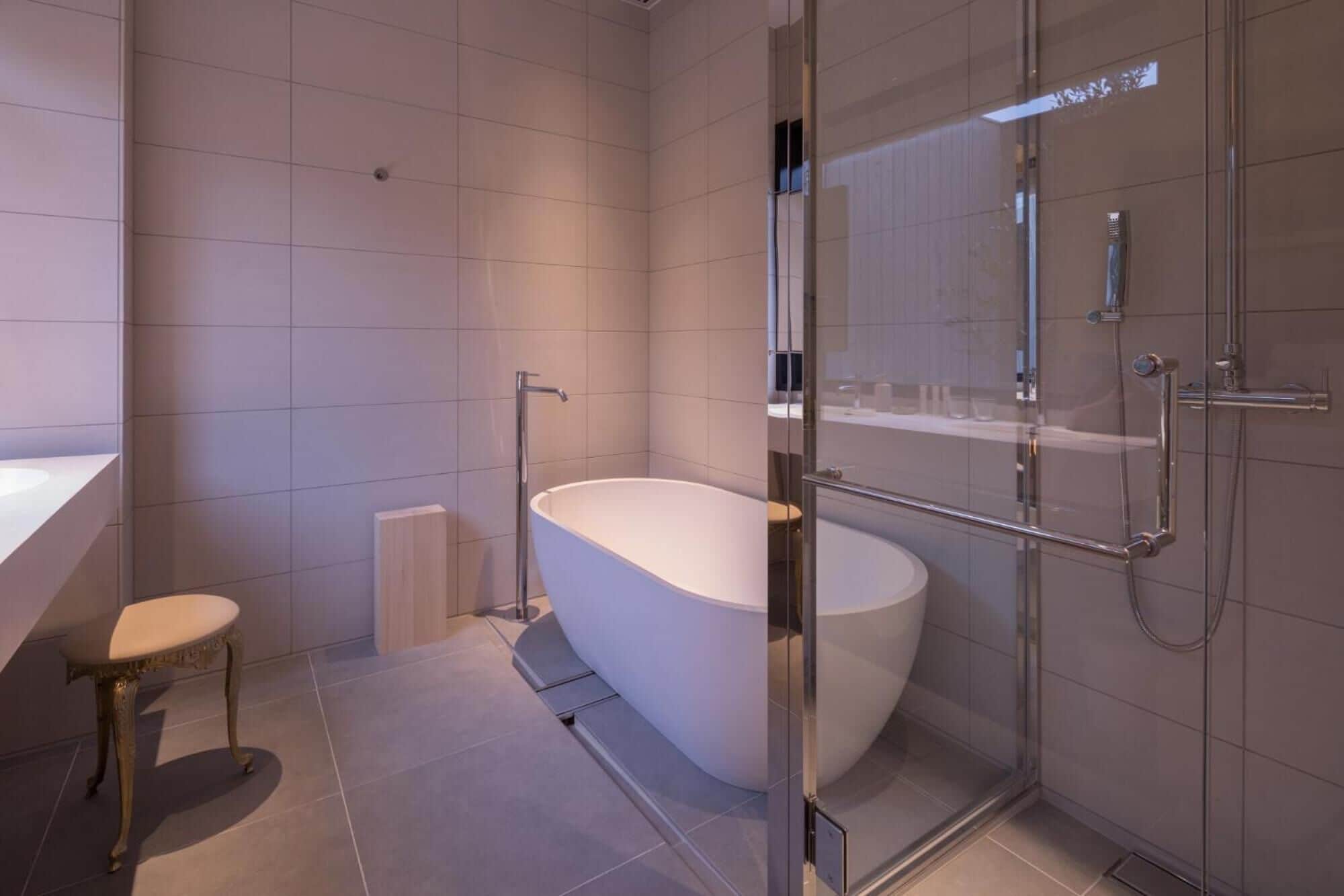A modern bathroom with a freestanding bathtub, a glass-enclosed shower, and a vanity with a mirror.