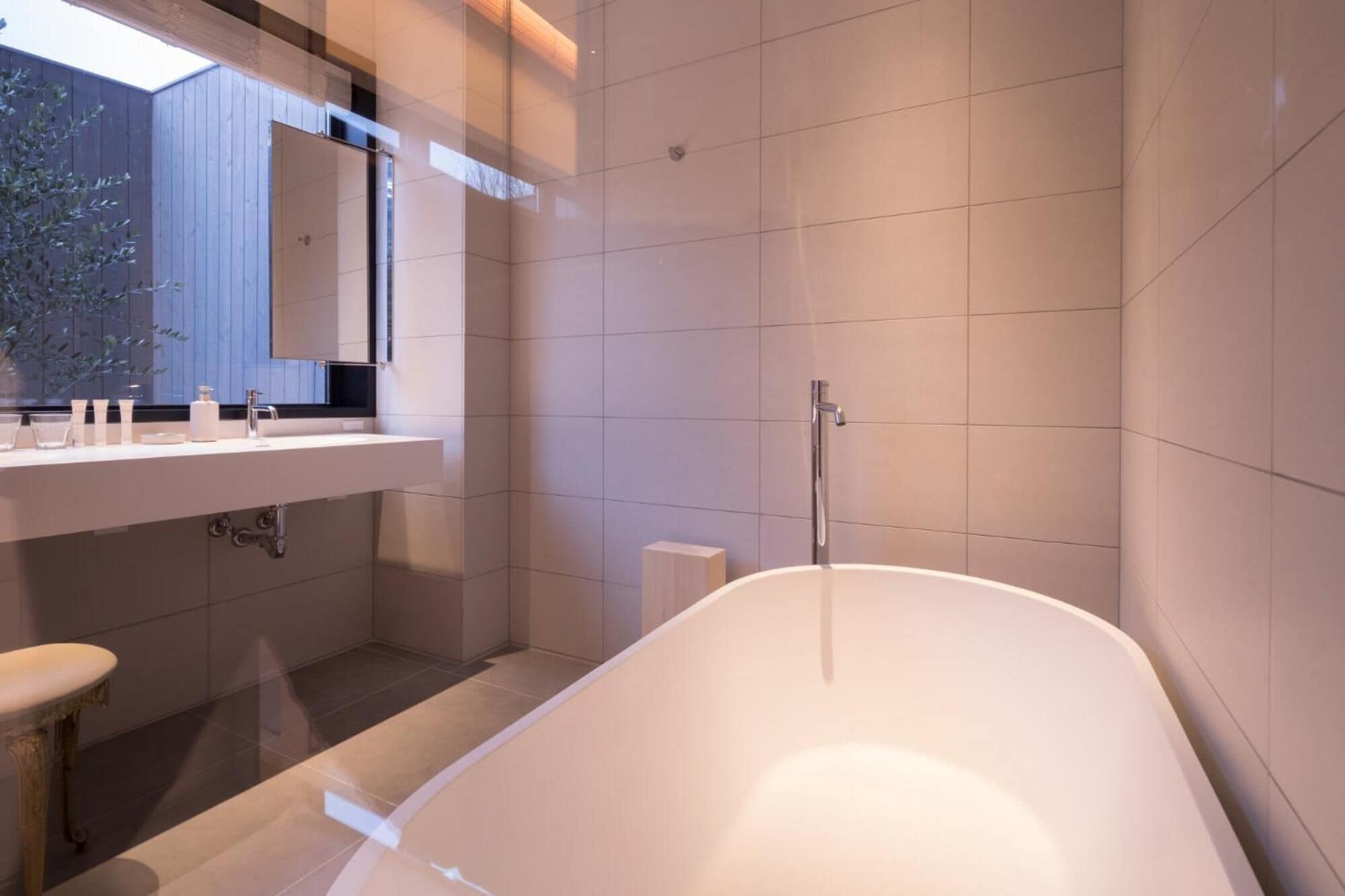 A modern bathroom with a freestanding bathtub, a vanity with a mirror, and a shower area.