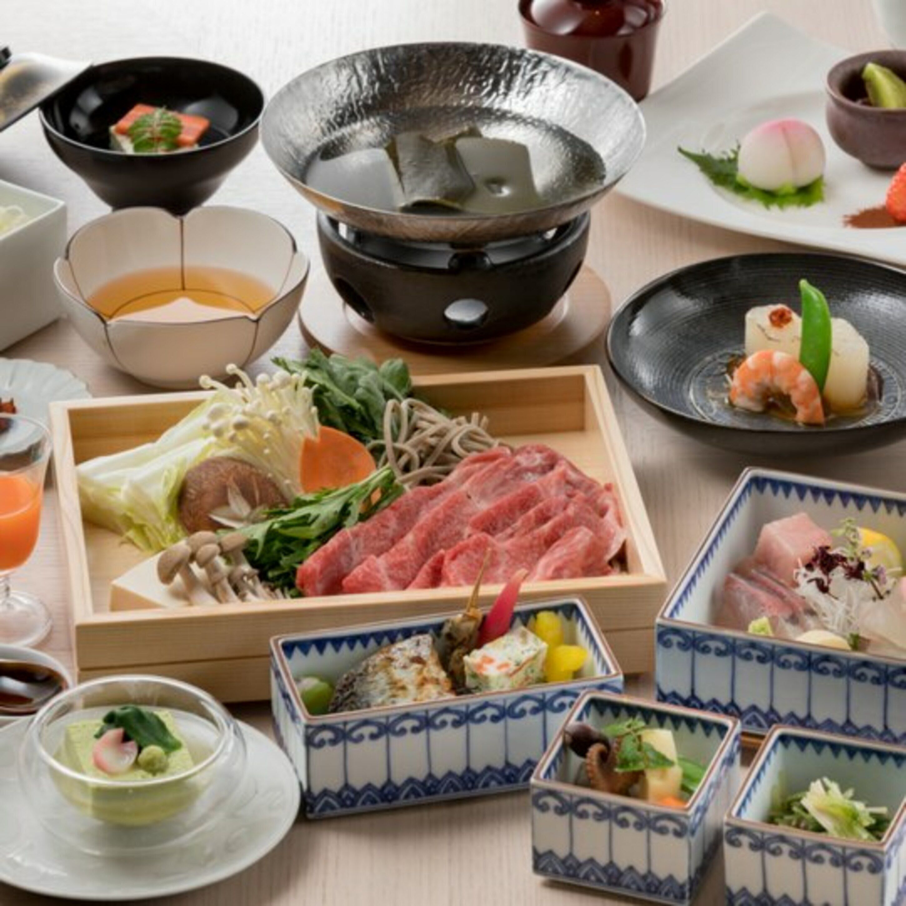A variety of Japanese dishes, including sushi and sashimi, served on a wooden table.