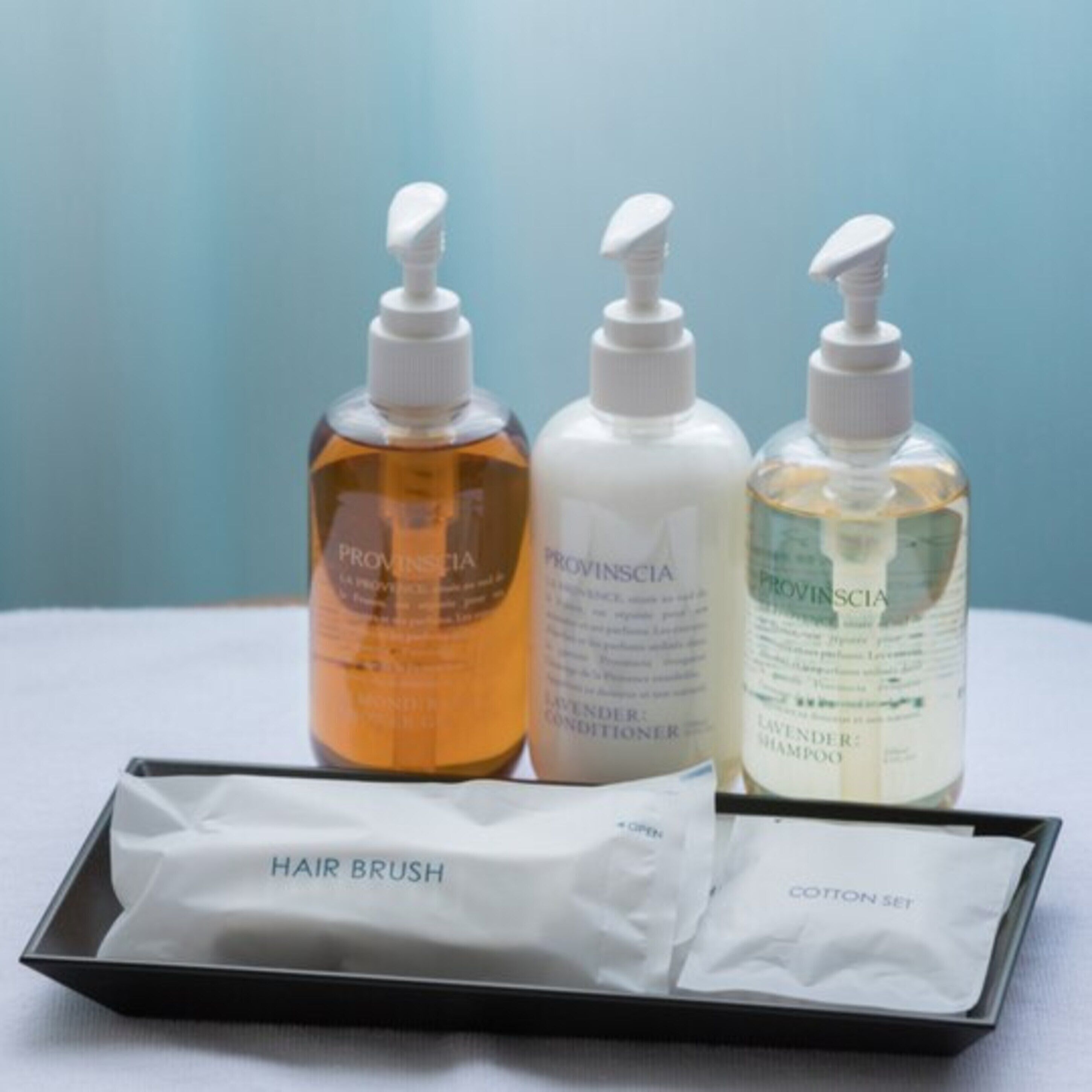 Tres botellas de productos capilares Provincía y un set de cepillos para el cabello.