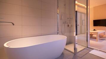 Ein modernes Badezimmer mit einer freistehenden Badewanne, einer Duschkabine aus Glas und einem sichtbaren Waschbeckenbereich.