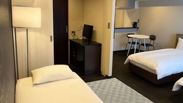 Une chambre d’hôtel avec deux lits, un bureau, une chaise, une petite table et un téléviseur.