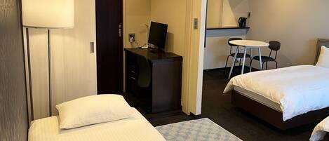 Een hotelkamer met twee bedden, een bureau, een stoel, een tafeltje en een televisie.