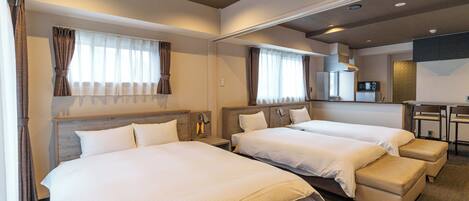 A hotel room with two beds, a kitchenette, and a seating area.
