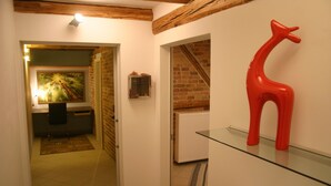 Ein Flur mit einer roten Giraffenskulptur auf einem Glastisch, einem Bild an der Wand und einer Tür zu einem anderen Raum.