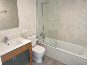 A modern bathroom with a glass-enclosed shower, a white toilet, and a sink with a wooden vanity.