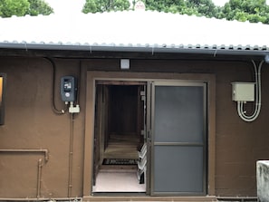 A building entrance with a metal door, a utility box, and a tiled floor leading to a hallway.