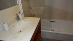 Een badkamer met een wit wastafel, een spiegel en een douchecabine met glazen wanden.