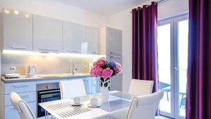 Eine moderne Küche mit weißen Schränken, einer Kaffeemaschine und einem Blumenstrauß auf der Arbeitsplatte.