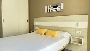 Ein Schlafzimmer mit Bett, Nachttisch, Wandleuchte und einem Schild mit dem Schriftzug 'Home'.