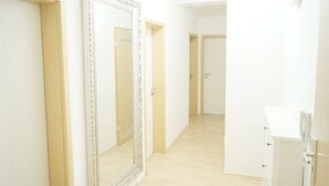 A hallway with a large mirror, wooden flooring, and white walls. - F10 APARTMENT Ulm • Apartment in the heart of Ulm (Ulm)