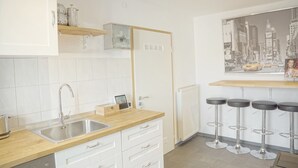A modern kitchen with white cabinets, a stainless steel sink, wooden countertops, and a bar area with stools. - F10 APARTMENT Ulm • Apartment in the heart of Ulm (Ulm)
