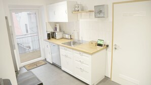 A modern kitchen with white cabinets, a wooden countertop, a sink, and a built-in oven. - F10 APARTMENT Ulm • Apartment in the heart of Ulm (Ulm)