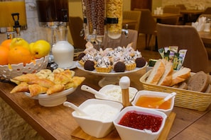 A buffet table with various food items including pastries, bread, and condiments. - King David Bakuriani (Borjomi)