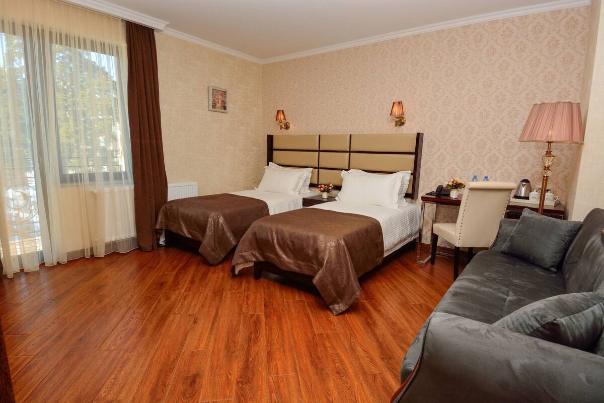 Une chambre d’hôtel avec deux lits, un canapé, un bureau et une chaise.