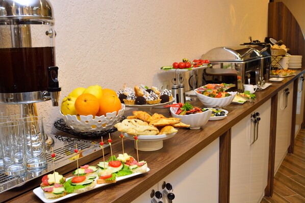 A buffet with various food items, a coffee machine, and a fruit bowl.