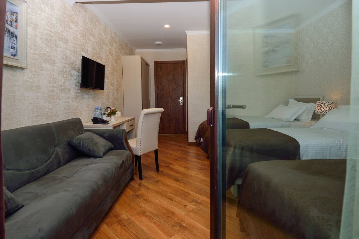 Une chambre d’hôtel avec un canapé, un bureau et une chaise, une télévision et deux lits.