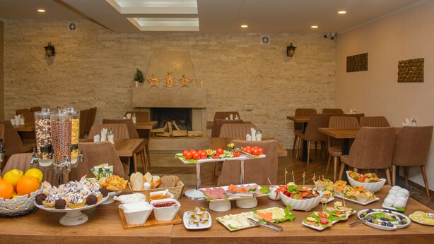 A buffet setup with various food items and a fireplace in the background. - King David Bakuriani (Borjomi)