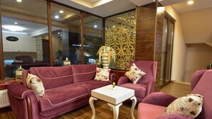 A modern living room with a red sofa, a white coffee table, and a large window with a view of the street. - King David Bakuriani (Borjomi)