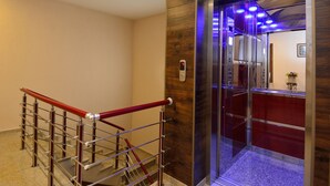 A modern elevator with a wooden panel design and a red handrail. - King David Bakuriani (Borjomi)