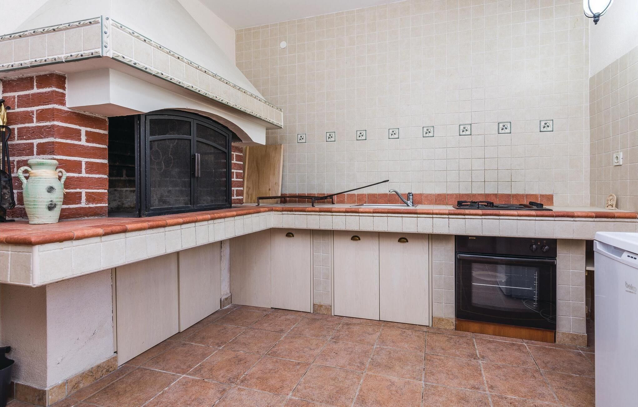 Una cocina con horno de ladrillo, estufa integrada y lavavajillas.