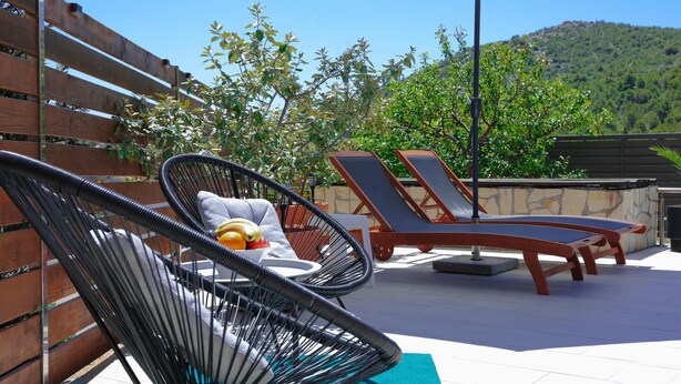 Een terras op het dak met twee lounge fauteuils, een kleine tafel en een fruitschaal.
