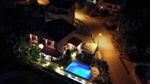 Een woonhuis met een zwembad, een overdekt terras en uitzicht op de straat.