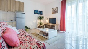 A modern living room with a sofa, coffee table, TV, and plants. - Gorgeous apartment in Pula with WiFi (Pula)