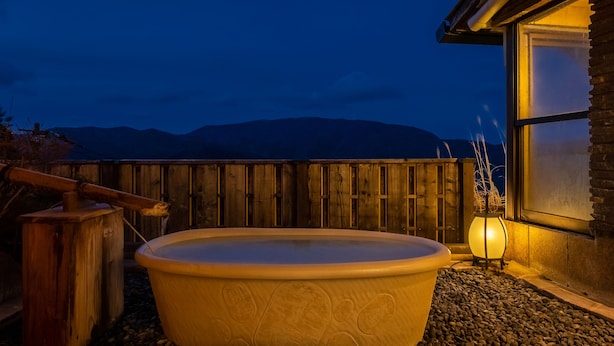 A hot tub in a covered outdoor area with a wooden fence and a stone pathway. - Shirayu no Yado Yamadaya (Hakone)