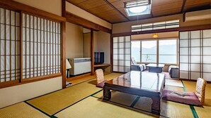 A traditional Japanese room with tatami flooring, a low table, cushions, sliding doors, and a television. - Shirayu no Yado Yamadaya (Hakone)