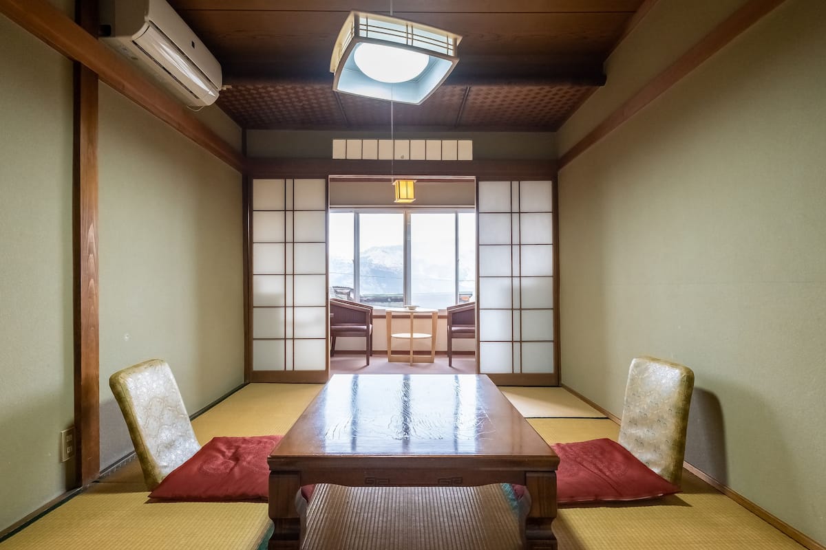 Une pièce de style japonais traditionnel, avec un sol recouvert de tatamis, une petite table en bois et des paravents en papier de riz (shoji).