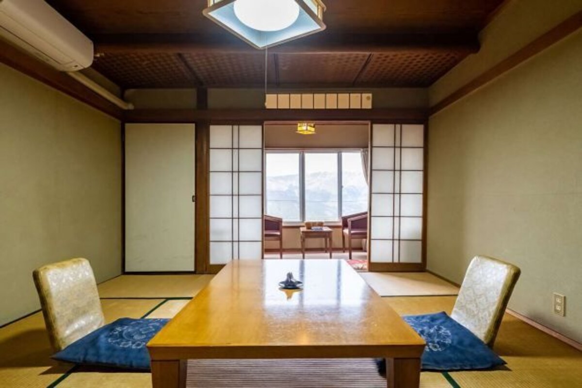 Una habitación japonesa tradicional con suelo de tatami, una mesa baja y puertas correderas.