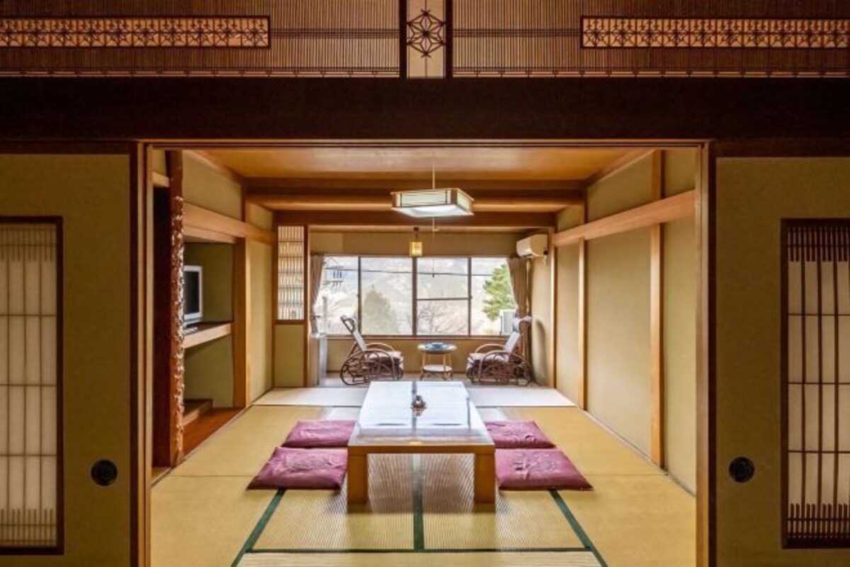 Une pièce de style japonais traditionnel, avec un sol recouvert de tatamis, une table basse et deux chaises.