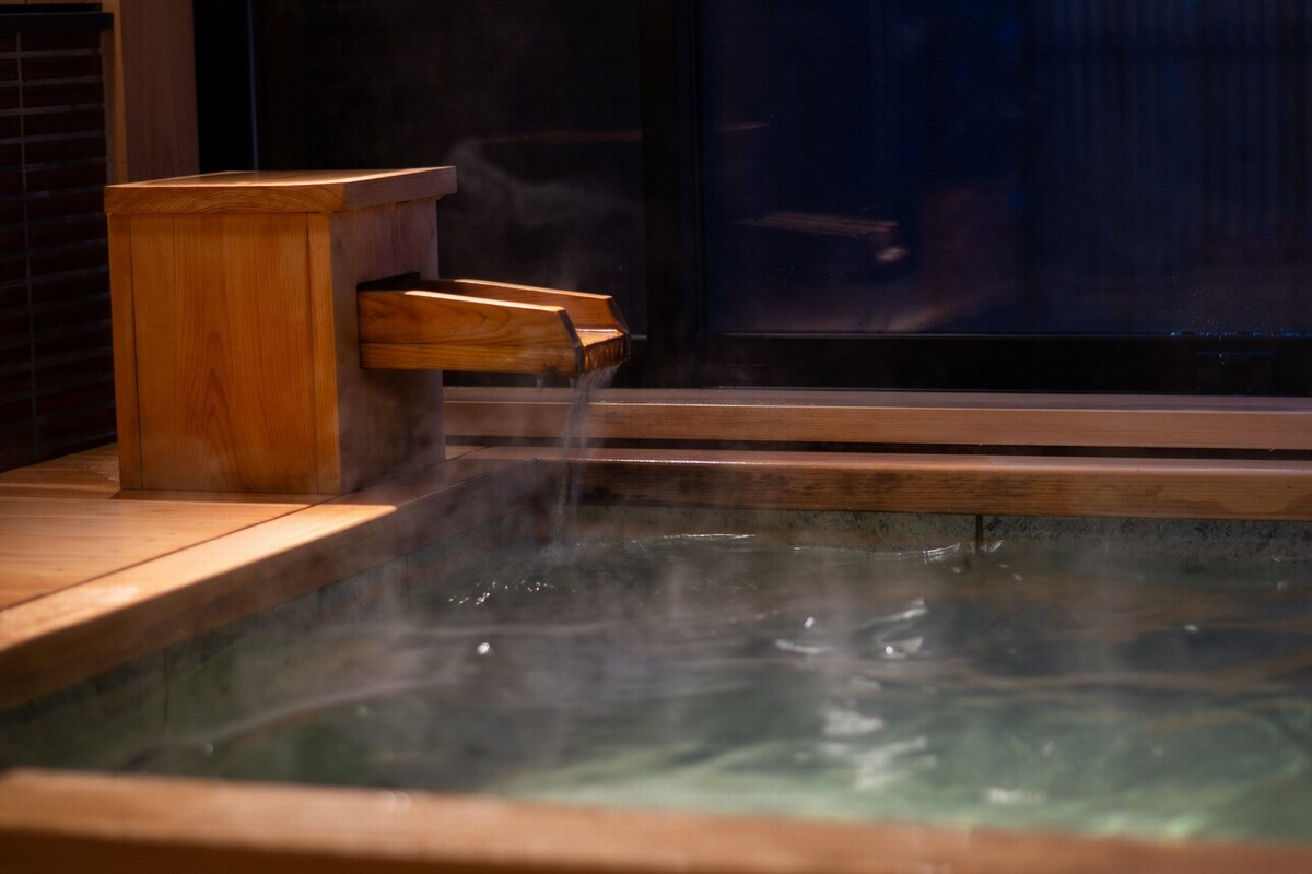 Une zone de sources chaudes avec un banc en bois et une cloison en verre.
