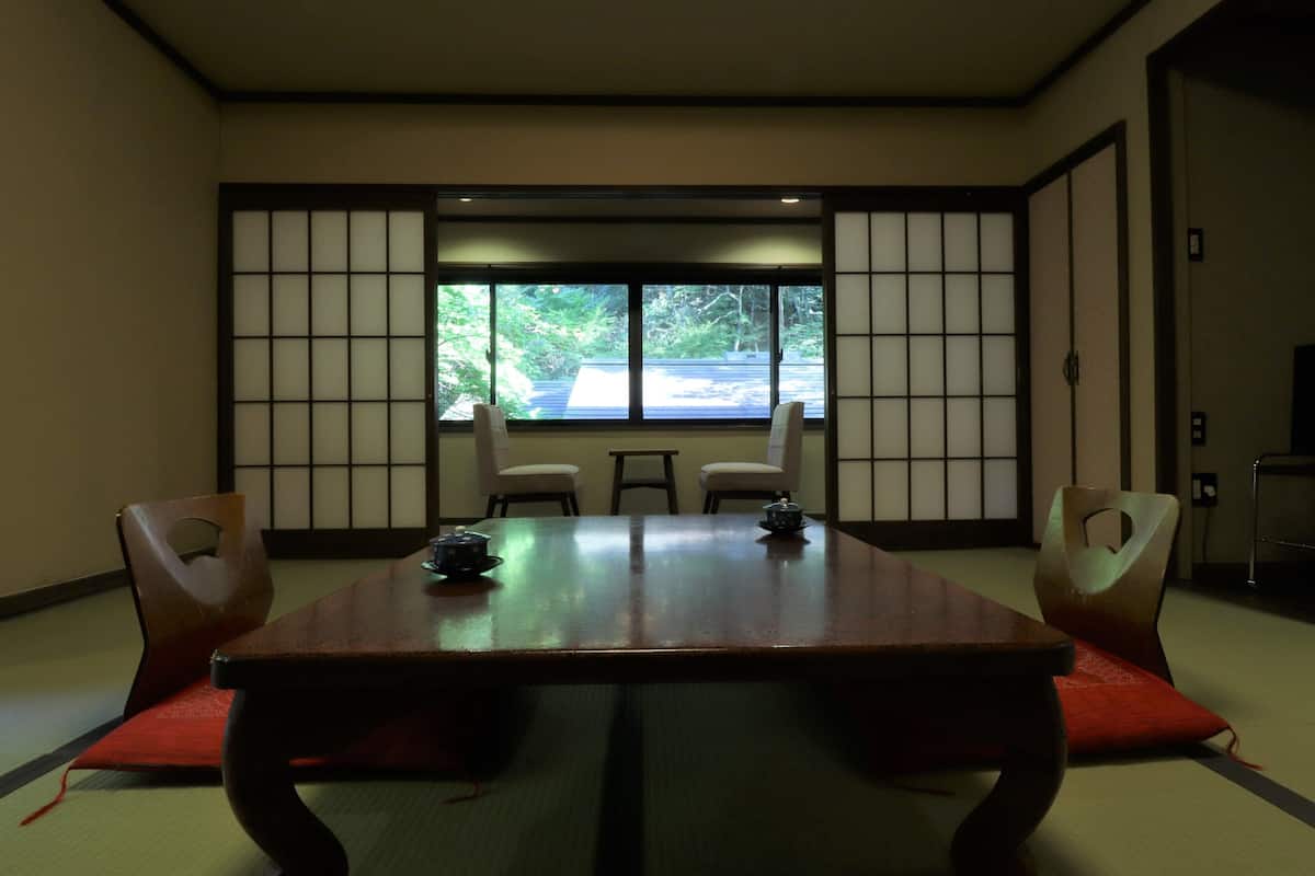 Una habitación japonesa tradicional con suelo de tatami, una mesa baja y paneles shoji.