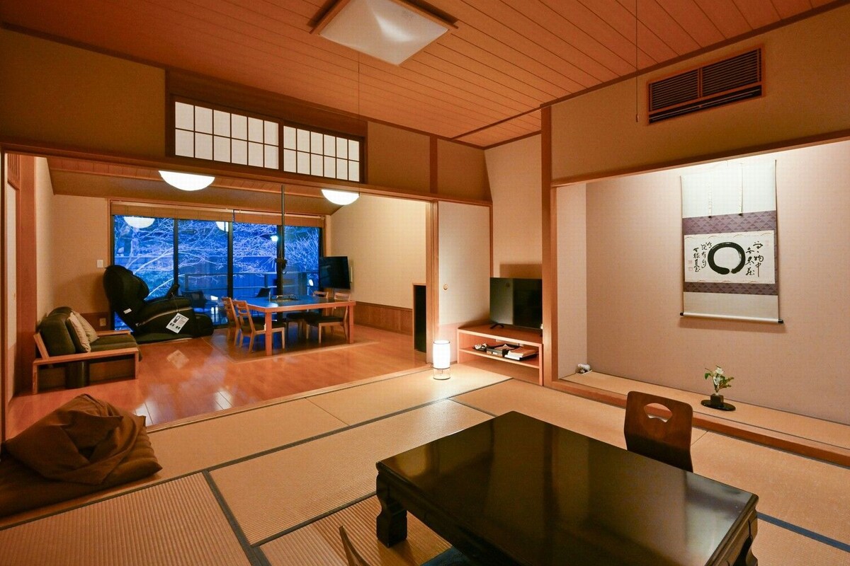 Ein traditioneller japanischer Raum mit Tatami-Böden, einem niedrigen Tisch und einem Fernseher.