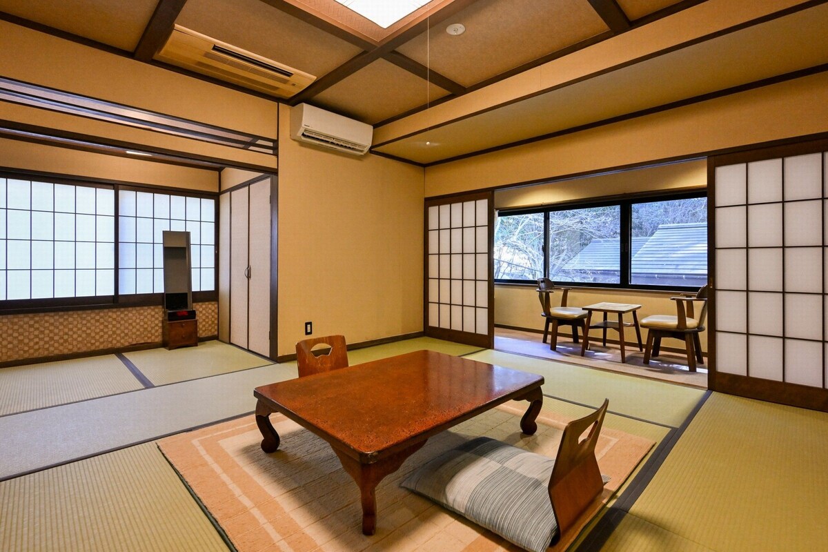Une pièce de style japonais traditionnel, avec un sol recouvert de tatamis, une table en bois et des portes coulissantes en papier de riz (shoji).