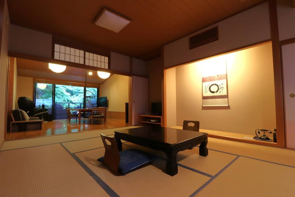 Una habitación tradicional japonesa con suelo de tatami, una mesa baja y puertas correderas.