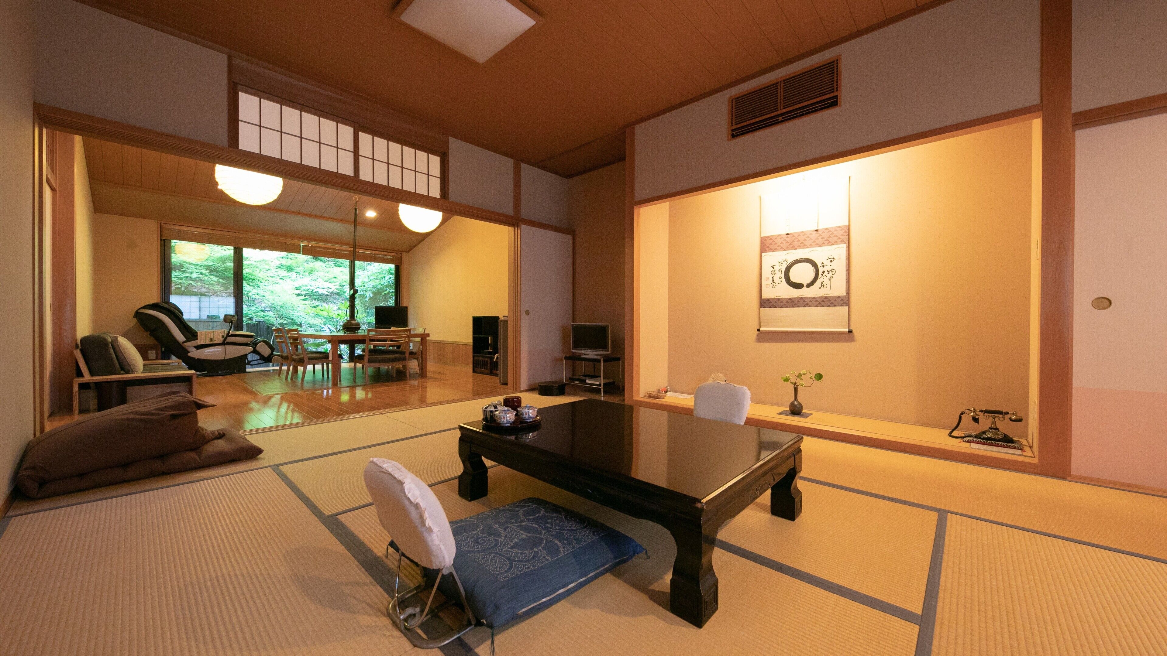 A traditional Japanese room with tatami flooring, a low table, a sofa, and a TV.