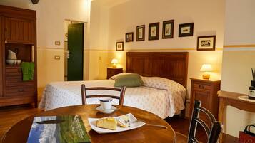 A neatly arranged hotel room with a bed, bedside tables, a dining table with a book and a plate of food, and a chair.