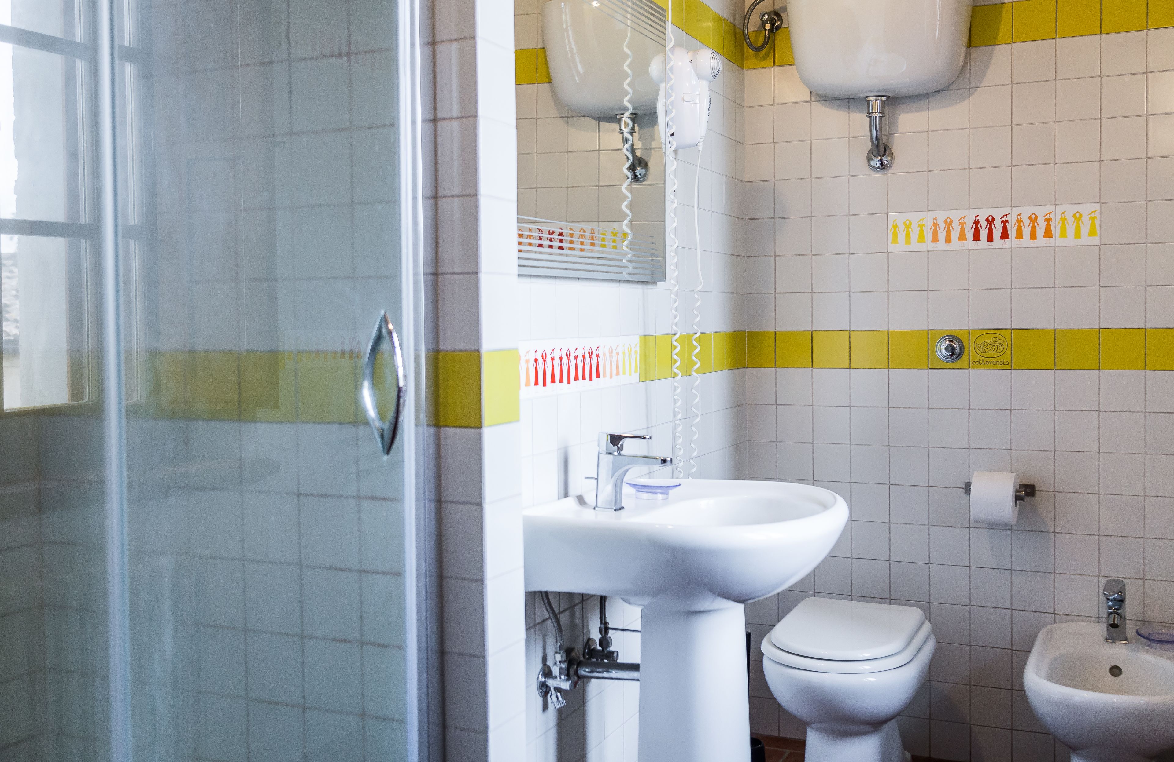Kylpyhuone, jossa on lasiseinäinen suihkukaappi, pesuallas, wc ja bidee.