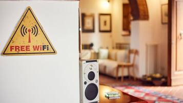 Una habitación con un letrero que indica 'Free WiFi', un altavoz y una colcha acolchada.