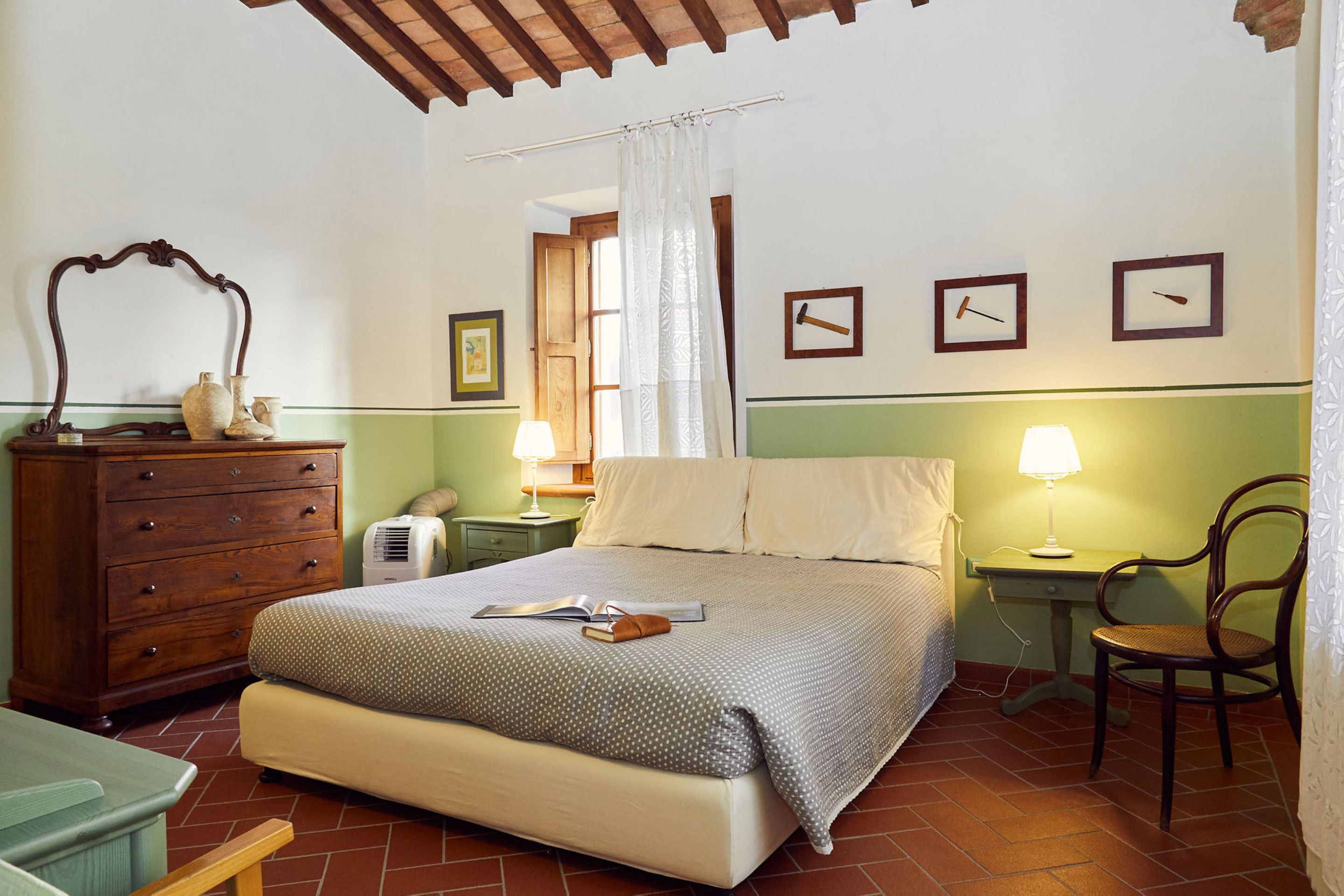 A bedroom with a bed, dresser, chair, and two bedside tables with lamps.