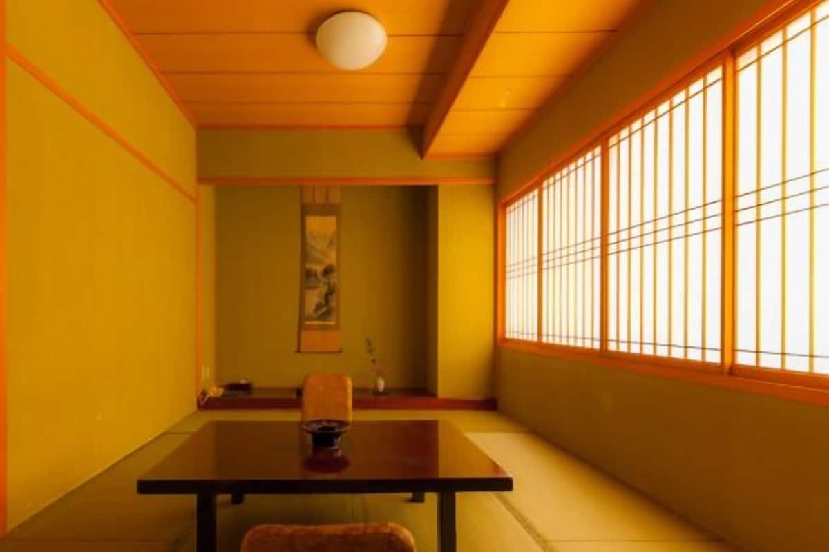 A traditional Japanese room with tatami flooring, a low table, a chair, and a shoji screen.