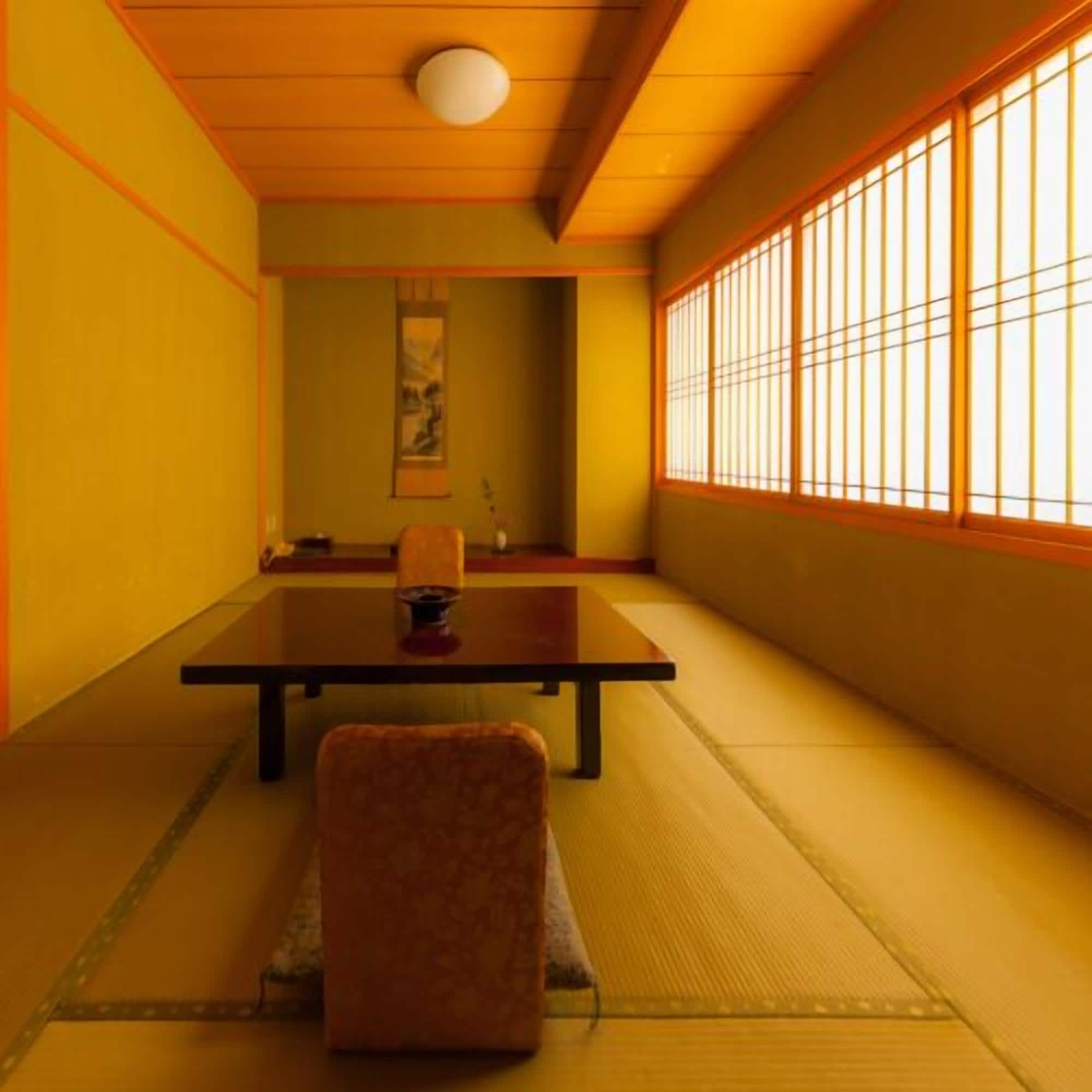 Una habitación japonesa tradicional con suelo de tatami, una mesa baja, una silla y un panel shoji.