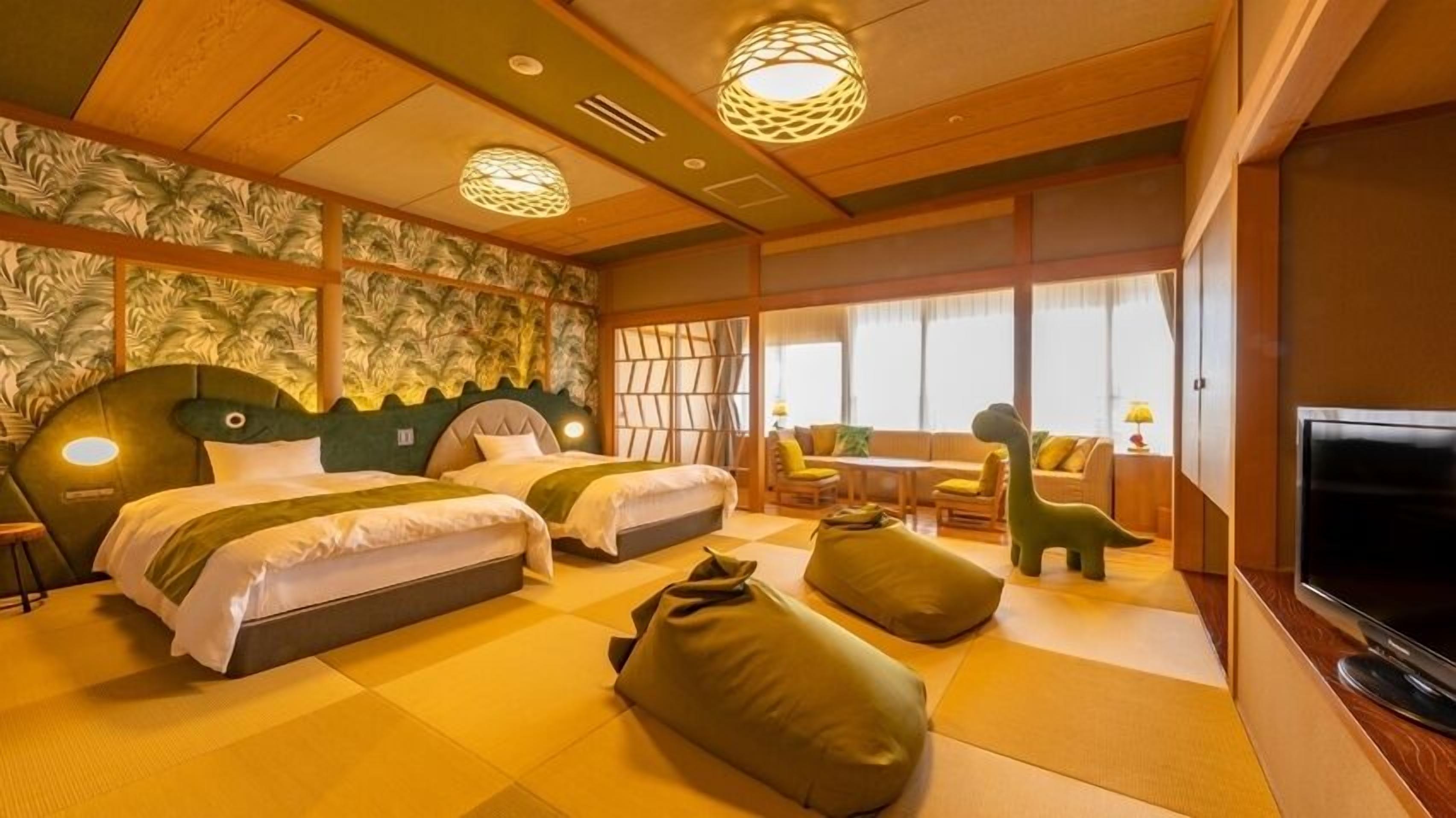 Una habitación de hotel con dos camas, un sofá, un televisor y una zona de comedor.